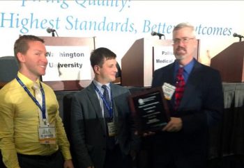 Moderator Mark Bowyer, MD, FACS, awards a plaque to Washington University general surgery residents Paul Evans, MD, left, and Joshua Sommovilla, MD, winners of the 2014 Surgical Jeopardy contest.